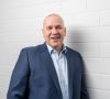Dr. Steffen Haack, Vorstandsvorsitzender der Bosch Rexroth AG im Anzug lehnt vor Mauer mit weißen Ziegelsteinen